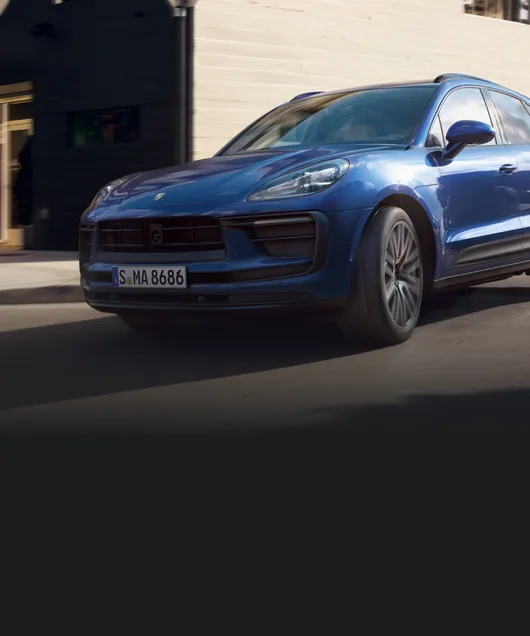 Porsche Macan in Gentian Blue Metallic driving through the city. Front and side views.