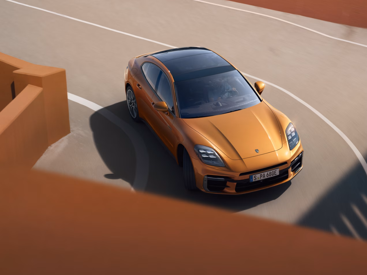 Porsche Panamera Turbo E-Hybrid in Madeira Gold Metallic navigating a bend. View of front and side from above.