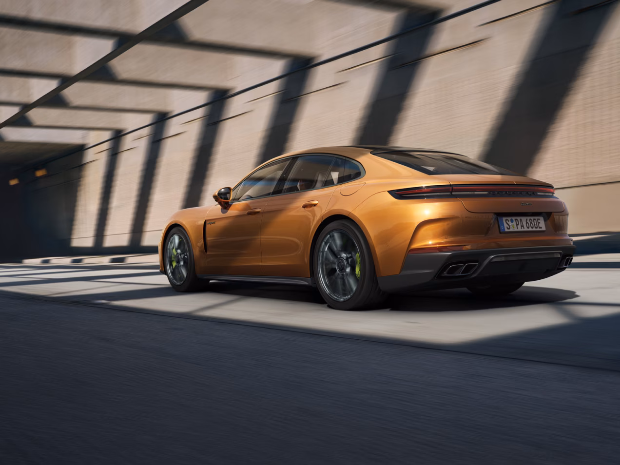 行驶在街道上的马德拉金属漆保时捷 Panamera Turbo E-Hybrid 从后面看的后侧视图