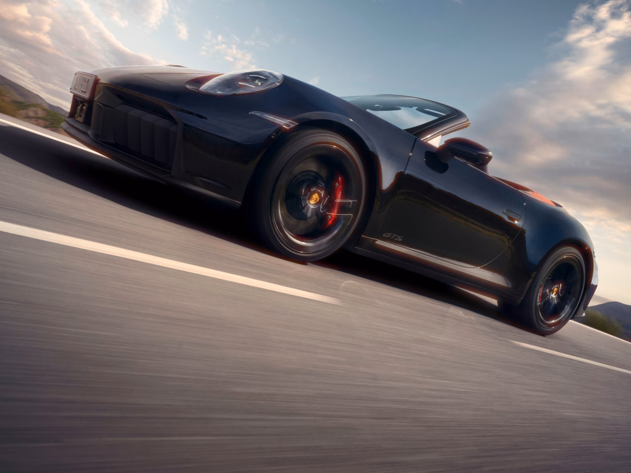 Porsche 911 Carrera GTS Cabriolet in Black driving on a road. Side view.
