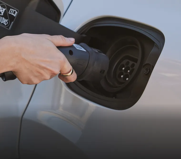 细节图：一个人将充电插头接入细花白金属漆保时捷 Cayenne E-Hybrid 插电式混合动力车型的充电口