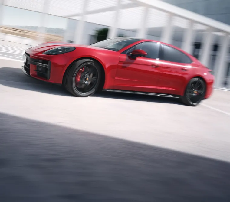 驶过城区的胭脂红保时捷 Panamera GTS 从后面看的后侧视图