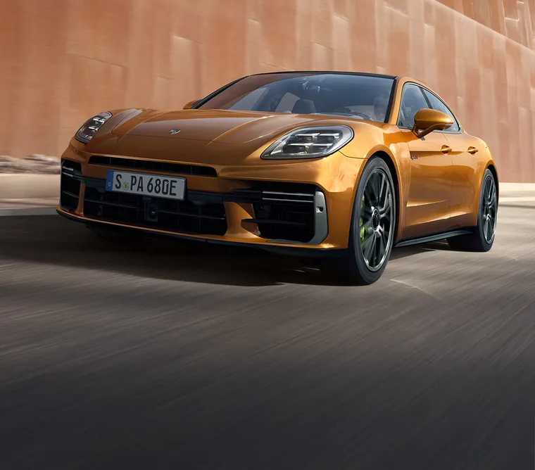 驶过金属墙的马德拉金属漆保时捷 Panamera Turbo E-Hybrid 从前面看的前侧视图