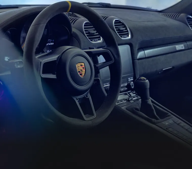 Porsche 718 Cayman GT4 RS interior: detailed view of the sports steering wheel with Yellow centre top marking.