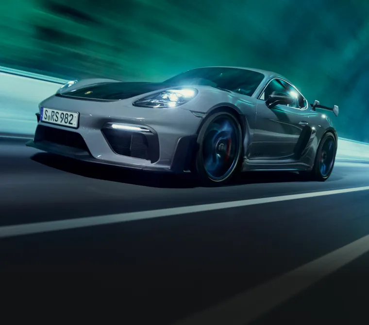 Porsche 718 Cayman GT4 RS in Arctic Grey with Weissach Package driving through a tunnel. Front and side views.