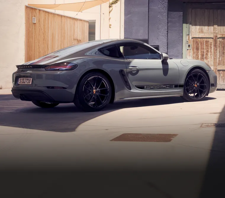 Porsche 718 Cayman Style Edition in Arctic Gray with Black Contrast Package parked in a residential area. View of the side and rear.