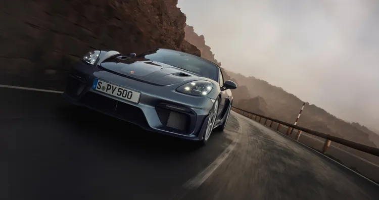 Porsche 718 Spyder RS in Vanadium Grey Metallic driving around a bend. Front and side view.