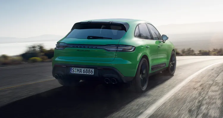 Porsche Macan GTS in Python Green driving along a country road. Rear and side view.
