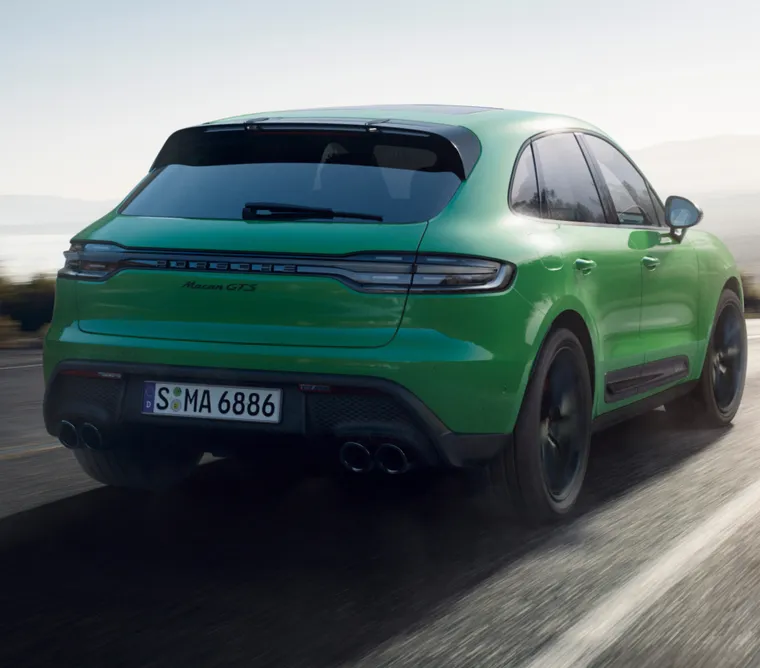 行驶在乡间公路上的巨蟒绿保时捷 Macan GTS。车尾后视图