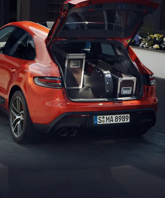 车道上的帕派雅橙金属漆保时捷 Macan S 装满行李的行李厢开启视图