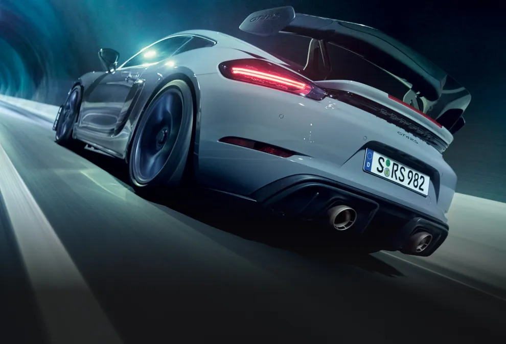 Porsche 718 Cayman GT4 RS in Arktikgrau mit Weissach-Paket fährt durch Tunnel. Blick auf Heck und Seite.