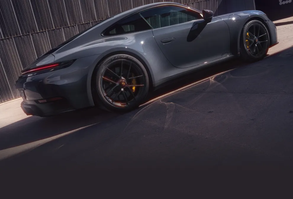 以深灰色墙壁为背景的板岩灰 Neo 保时捷 911 Carrera GTS 侧视图