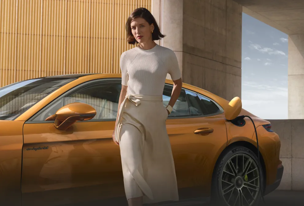 充电中的马德拉金属漆保时捷 Panamera Turbo E-Hybrid 侧视图前景中的一名女子离开车辆