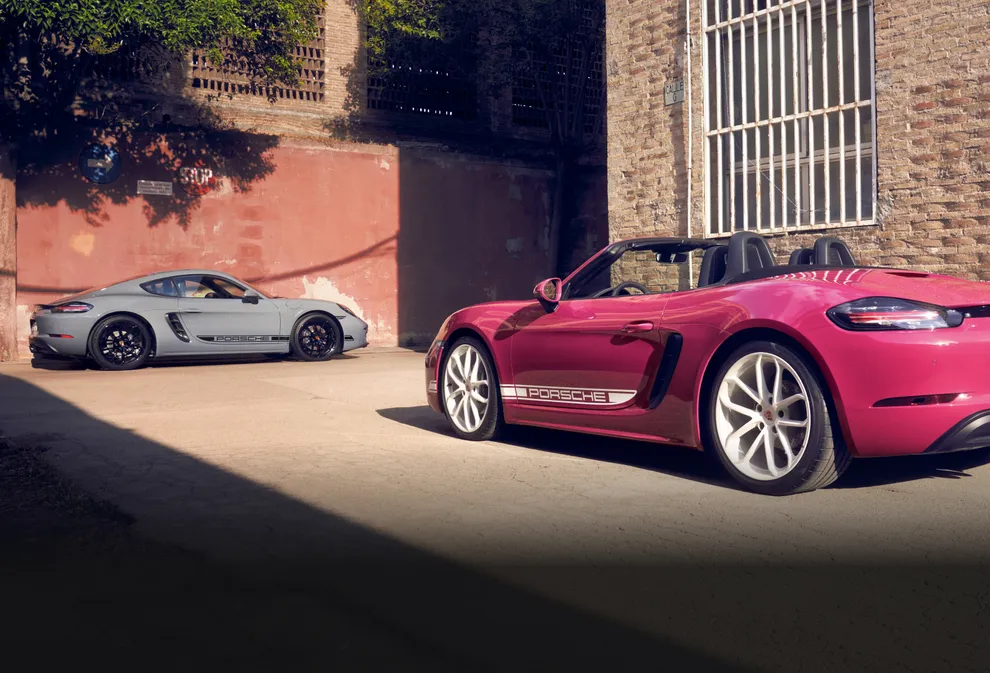 Porsche 718 Boxster Style Edition in Ruby Star Neo with White Contrast Package parked in front of 718 Cayman Style Edition in Arctic Gray with Black Contrast Package.