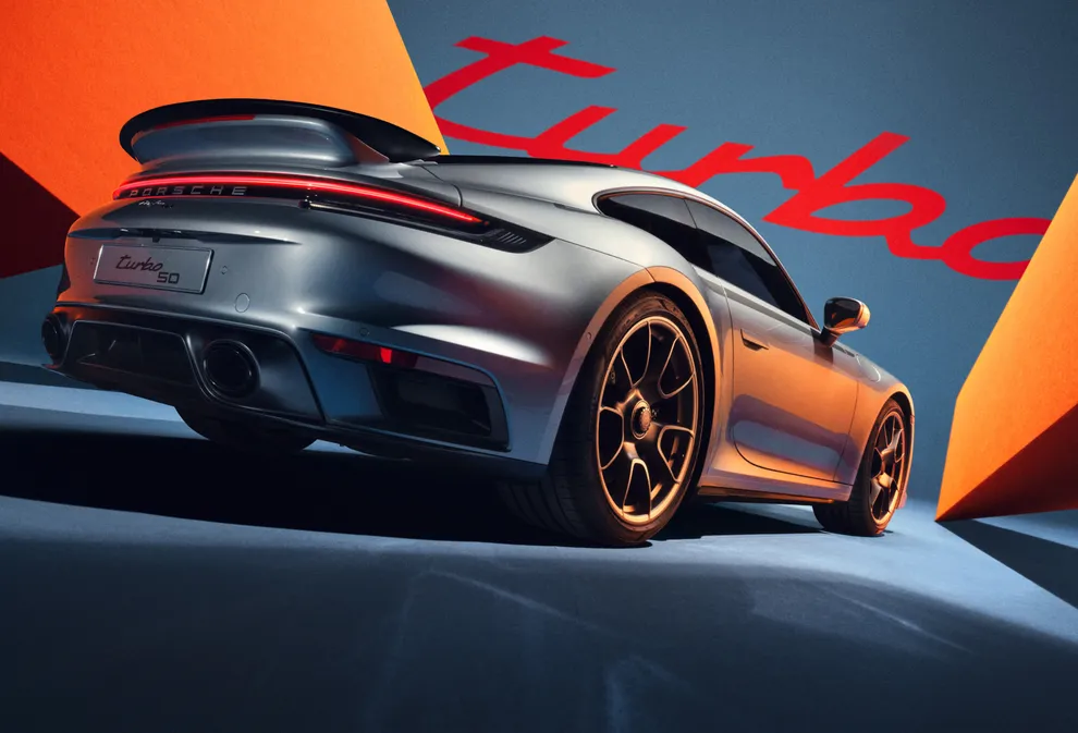 图片在蓝色/橙色背景下，从侧面和后面展示 GT 银金属漆保时捷 911 Turbo 50 周年纪念版车型 