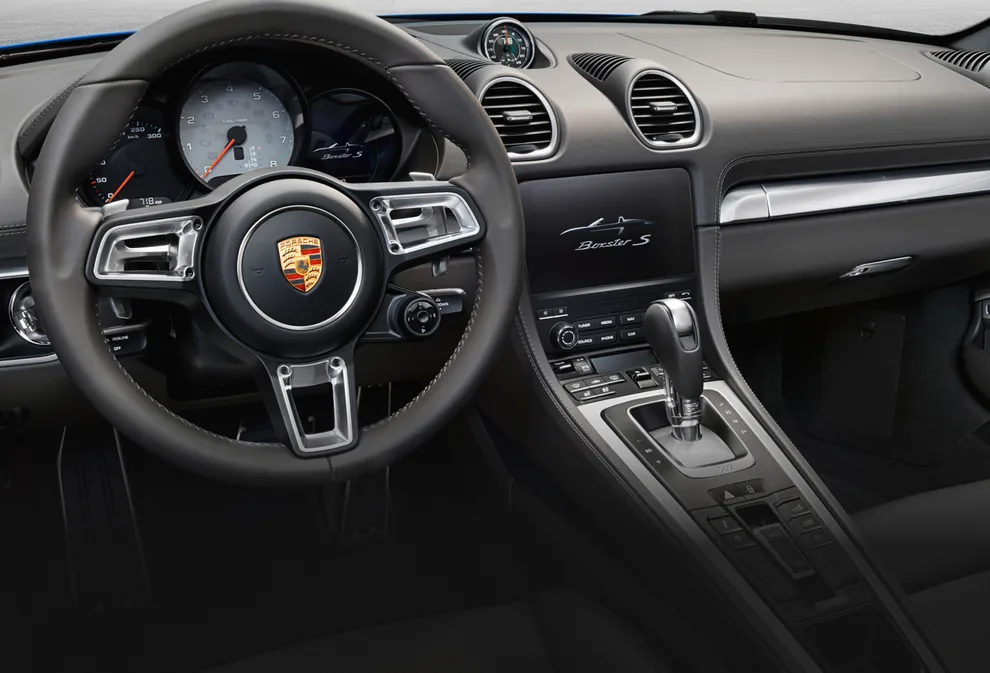 保时捷 718 Boxster S 的玛瑙灰内饰驾驶舱视图，重点聚焦中控台和方向盘