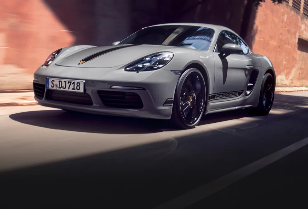 Porsche 718 Cayman Style Edition in Arctic Grey with Black Contrast Package driving through a town. Front and side views from the front.