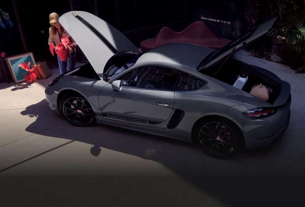 配备黑色对比色组件的极地灰保时捷 718 Cayman Style Edition，两个敞开的行李厢装满物品
