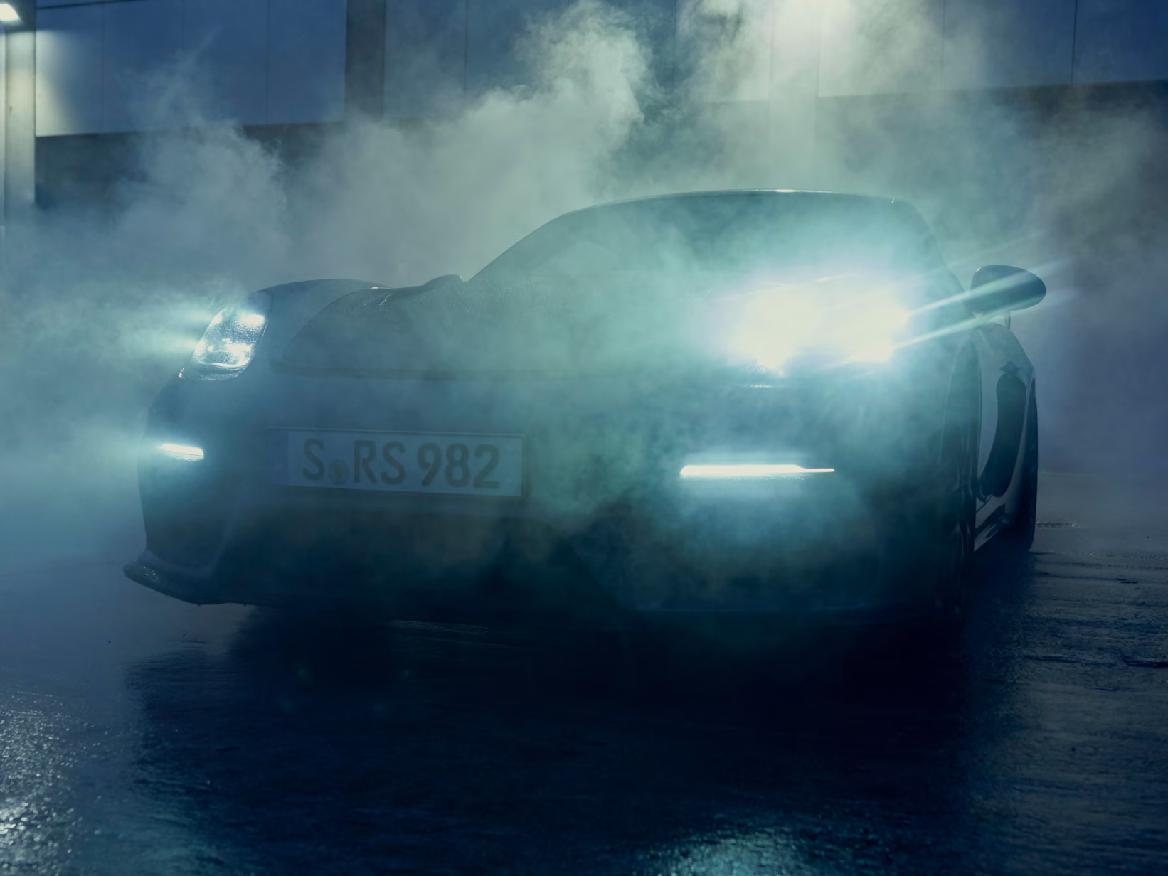 Porsche 718 Cayman GT4 RS parked in the fog with its lights on. Front view.