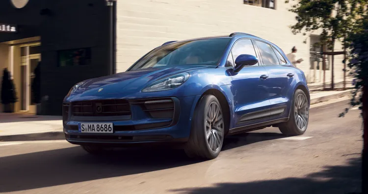 Porsche Macan in Gentian Blue Metallic driving through the city. Front and side views.