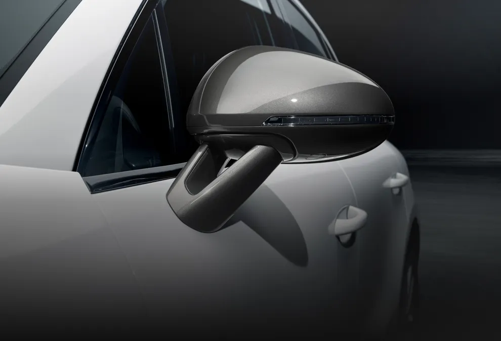 暗色背景衬托下的白色保时捷 Macan T 车外后视镜的细节图