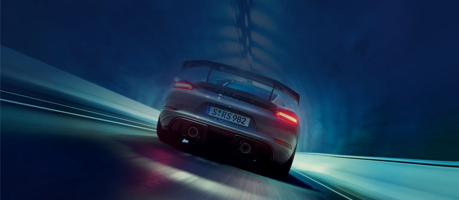 Porsche 718 Cayman GT4 RS in Arktikgrau mit Weissach-Paket fährt durch Tunnel. Blick auf das Heck mit Fokus auf die Endrohre.