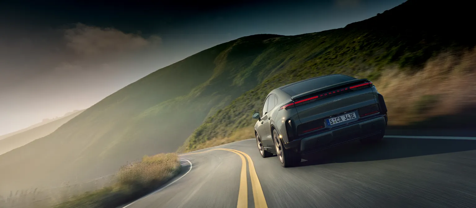 A Porsche Cayenne Turbo Coupé in Monteverde Metallic driving on a country road.