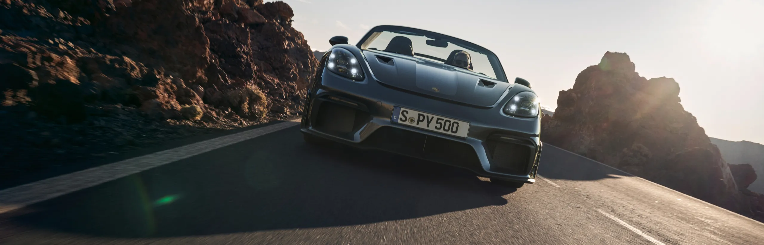 Porsche 718 Spyder RS in Vanadiumgraumetallic fährt durch Kurve. Sicht auf Front und Seite.