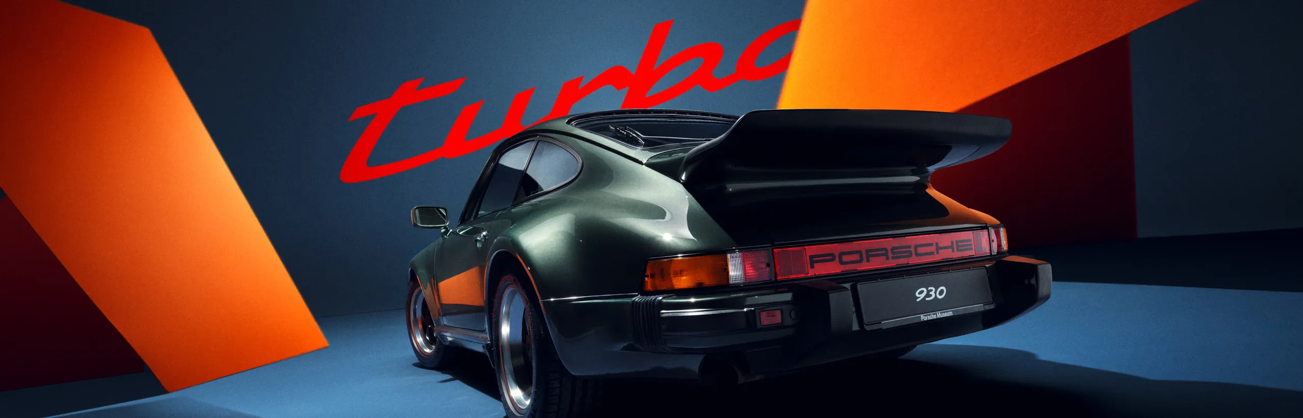 图片在蓝色/橙色背景下，从侧面和后面展示保时捷 911 Turbo (930) 