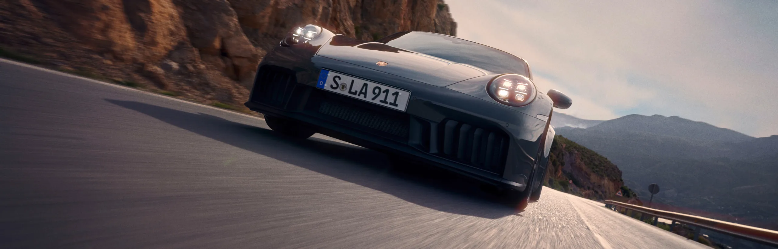 行驶在公路上的板岩灰 Neo 保时捷 911 Carrera GTS 从前面看的前视图