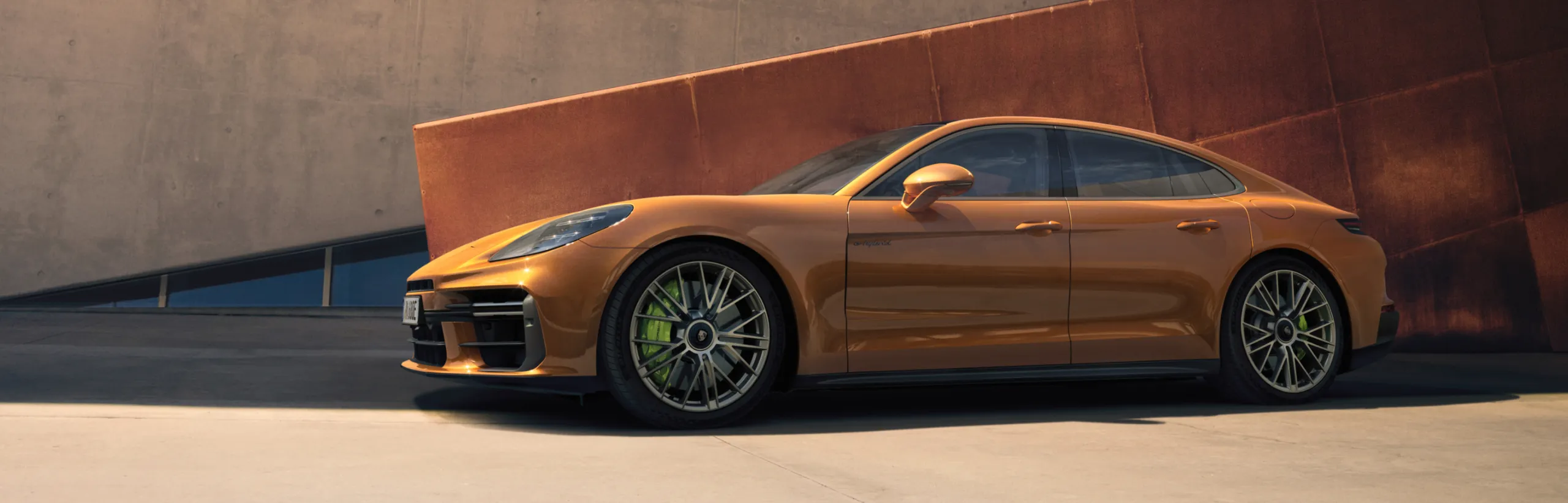 墙壁前停放的马德拉金属漆保时捷 Panamera Turbo E-Hybrid 侧视图