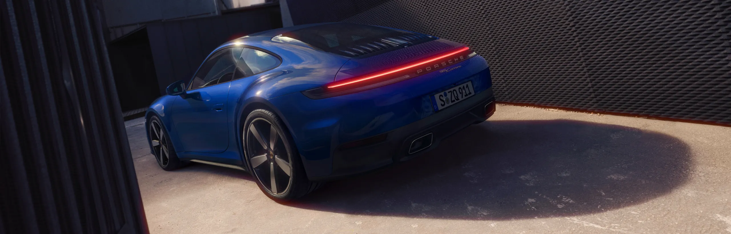 Porsche 911 Carrera GTS in Slate Grey Neo driving on a road. Front view from the front.