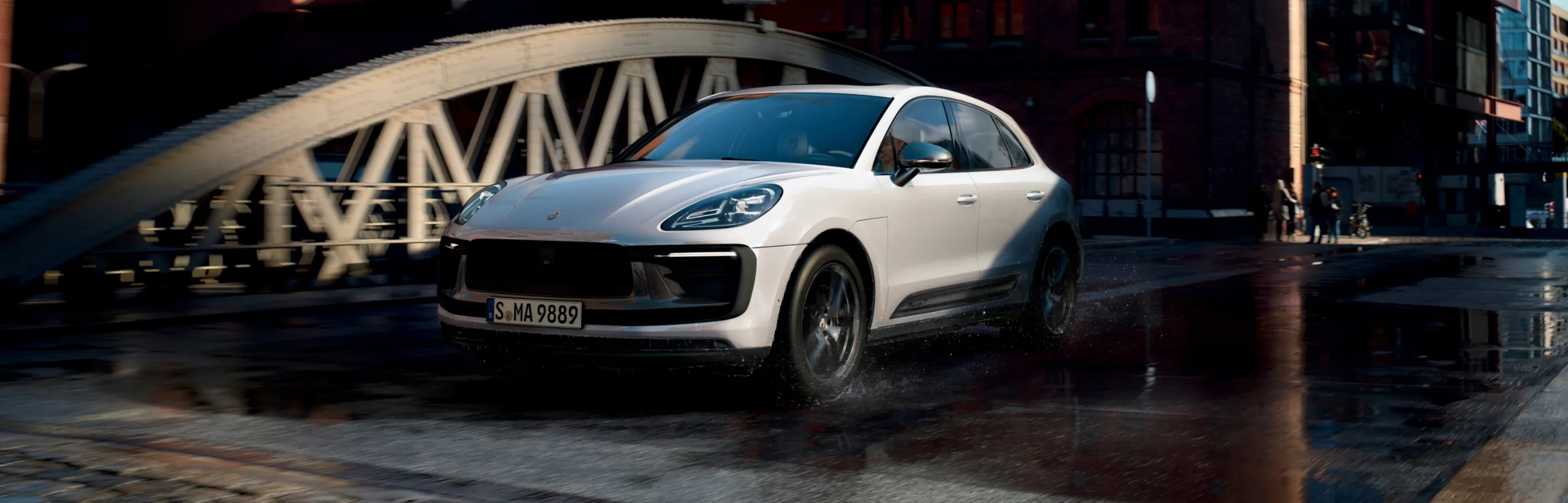 行驶在城市桥梁上的白色保时捷 Macan T 前视图和侧视图