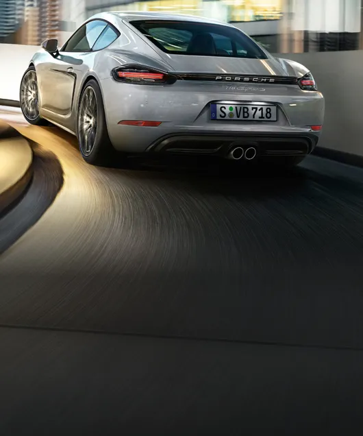 GT 银金属漆保时捷 718 Cayman S 驶过停车场。后侧视图