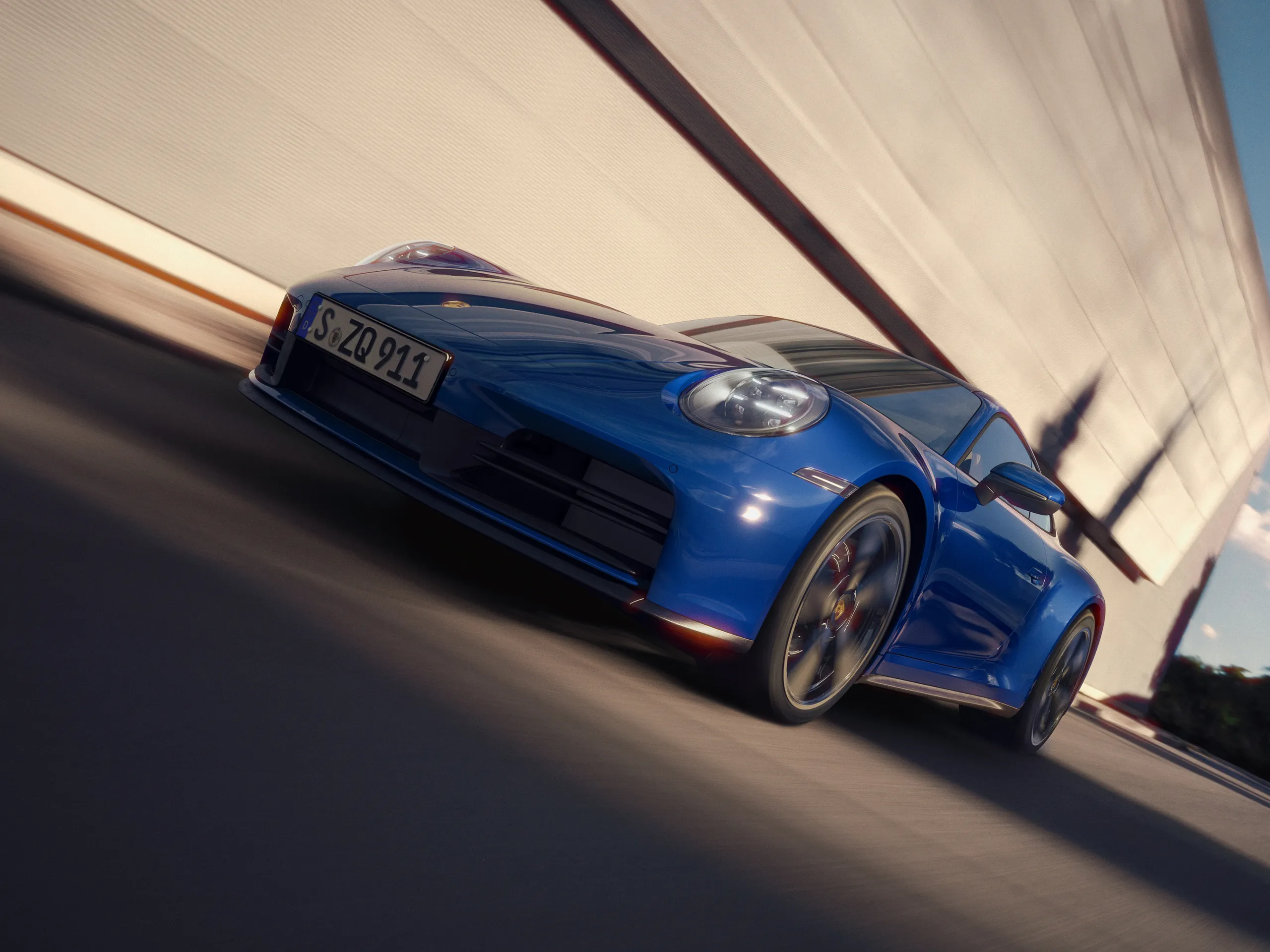 Front shot of a Luganoblue 911 Carrera driving on the road.